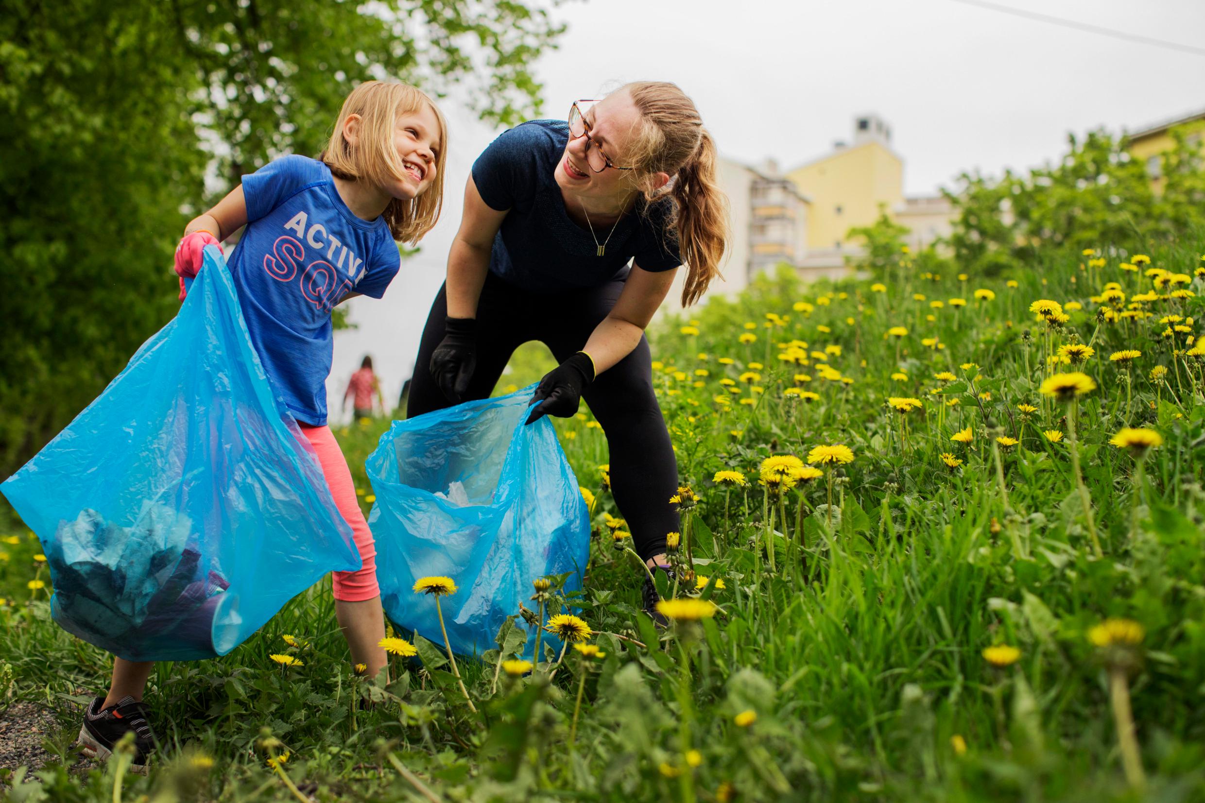 женщина и маленькая девочка собирают мусор в парке