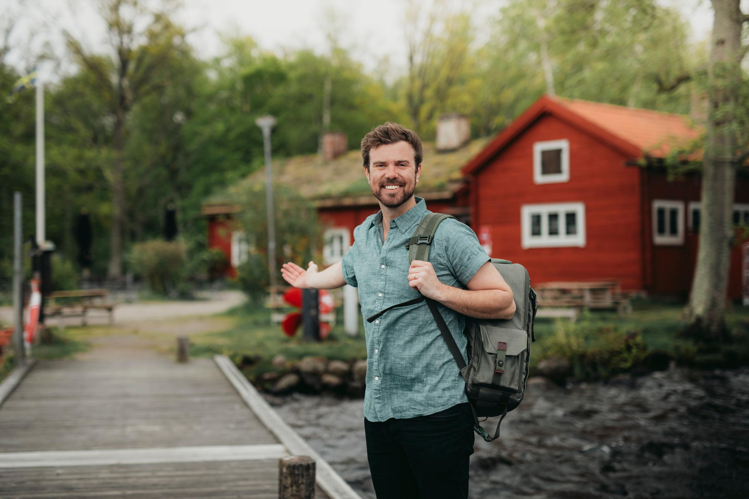 Мужчина с рюкзаком перед шведским традиционным красным домом
