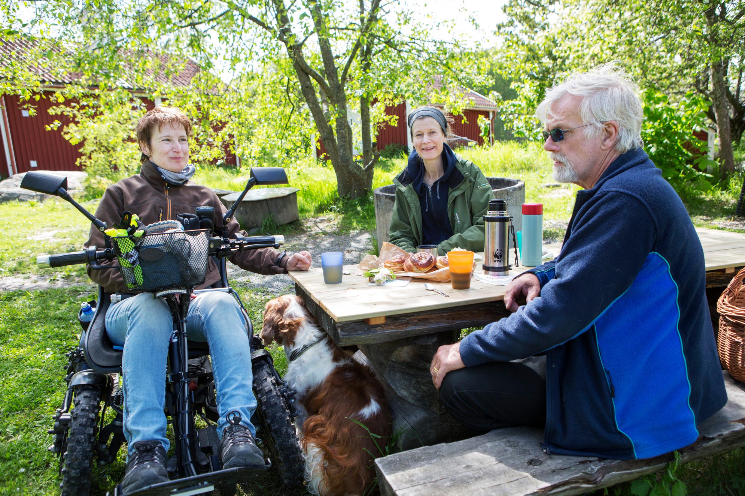 Друзья пьют кофе на природе, один из иних в инвалидной коляске