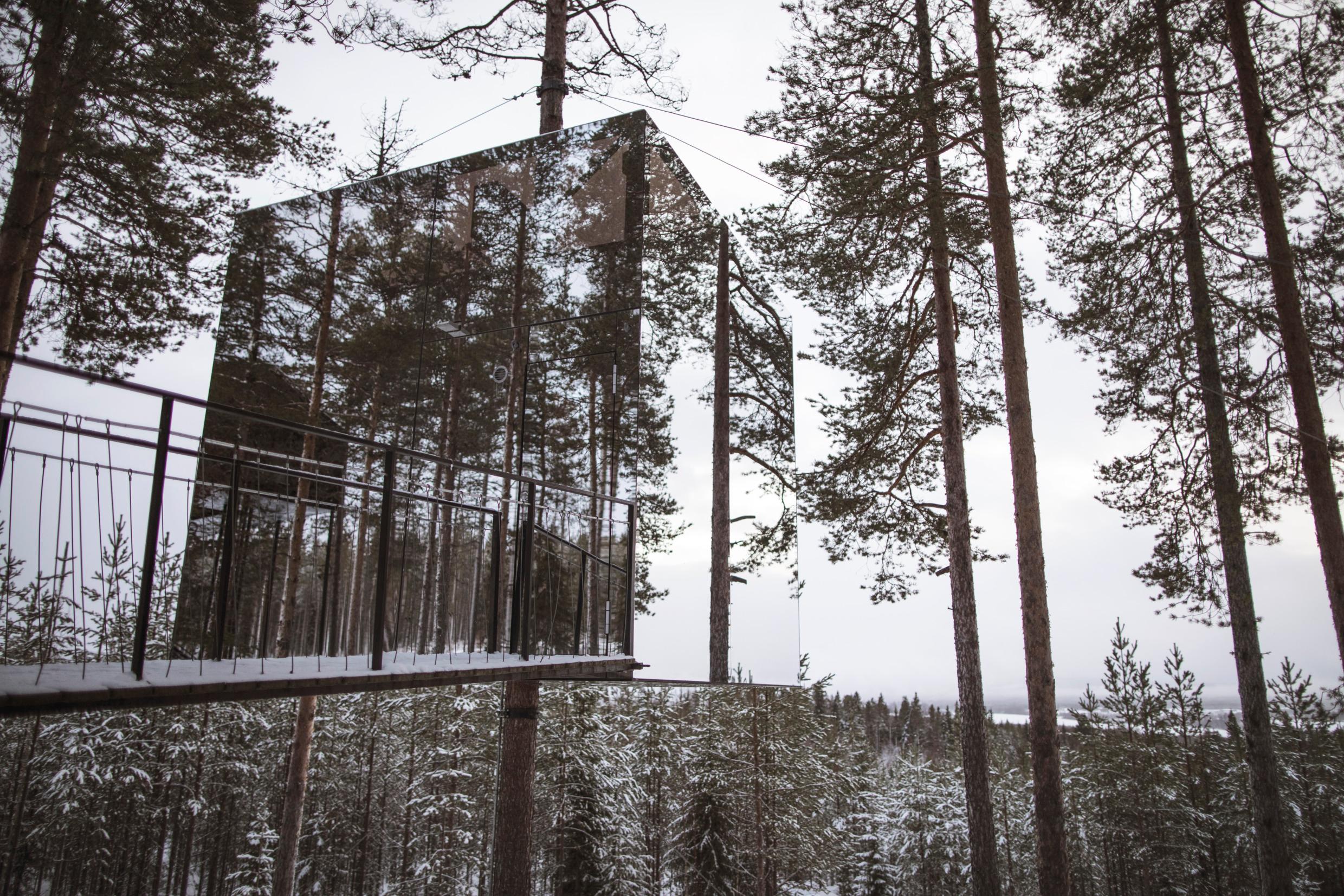 Дом на дереве из зеркального стекла, в заснеженном лесу в шведской Лапландии.