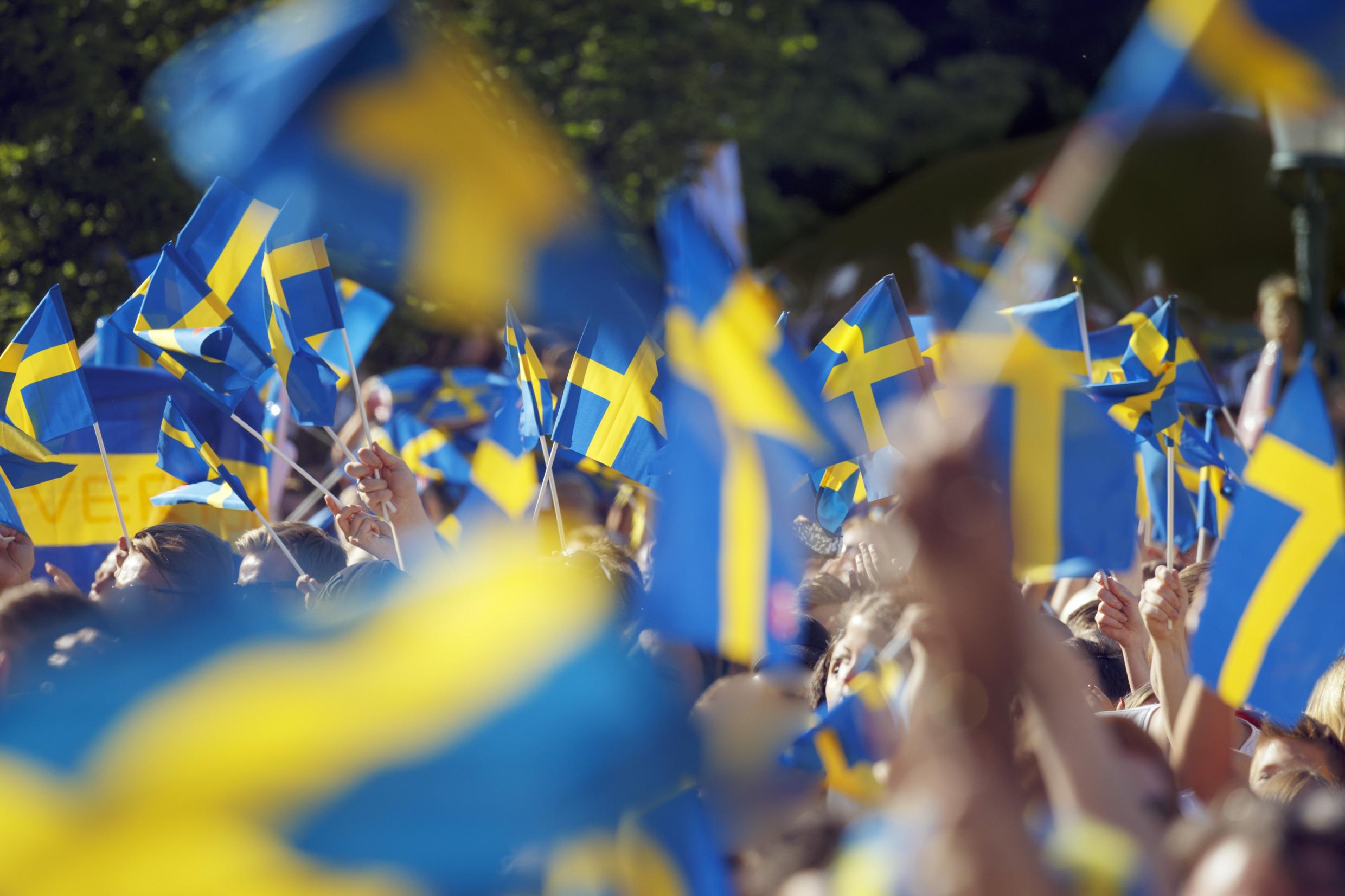 множество людей размахивает шведскими флагами